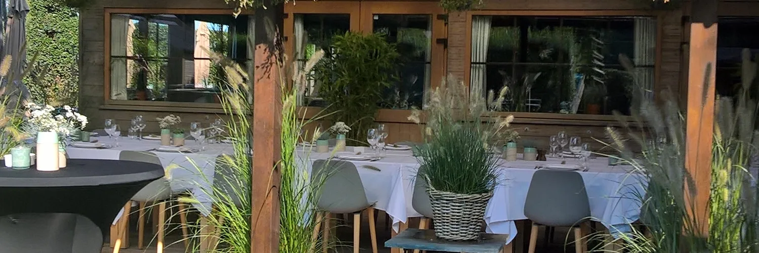 Overdekt terras met gedekte tafels, houten palen en siergrassen